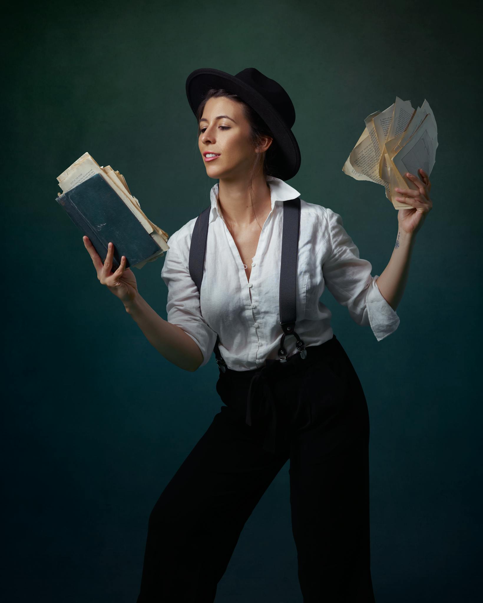 A woman in vintage attire holding a book and loose pages, posing gracefully.