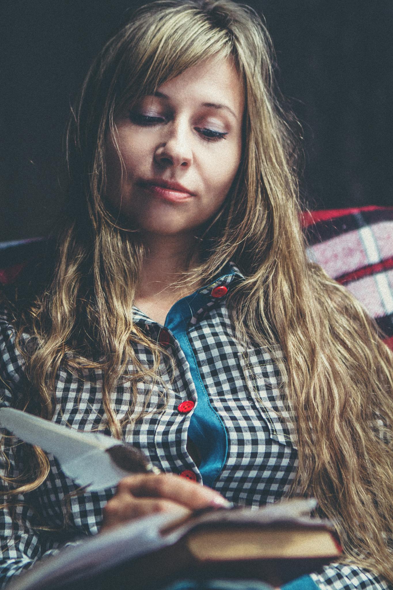 A young woman with long hair reading a book, creating a tranquil and thoughtful atmosphere.